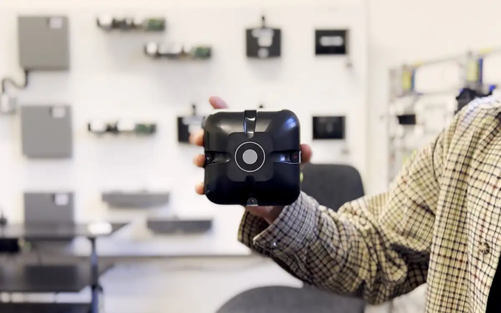 The DorMag Pro unit being held up to the camera. The unit is the main focus of the image with a blurred background of the Fireco testing room behind.